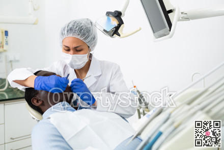 Woman stomatologist treating teeth to patient in dental office