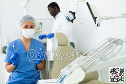 Portrait of a nurse with tools in her hands and wearing a medical mask in dental office