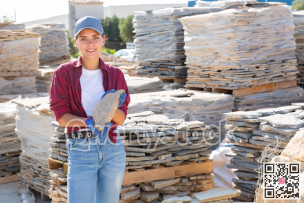 Female builder is choosing natural facing stone in the building store at an open-air construction site
