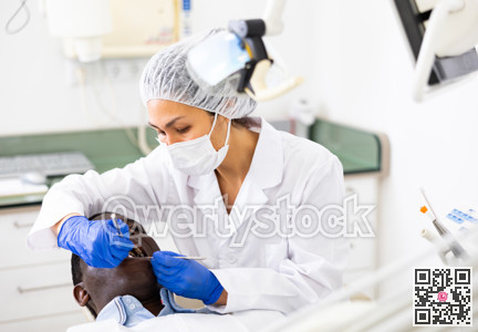 Dentist examining oral cavity of man in dental clinic