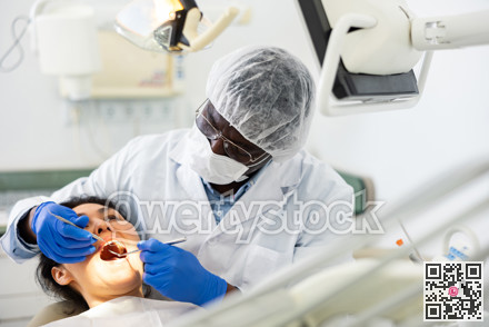 Male dentist using tools for tooth repairing on woman patient