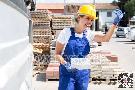 Female driver keeps records of materials when loading into back of truck at site of hardware store