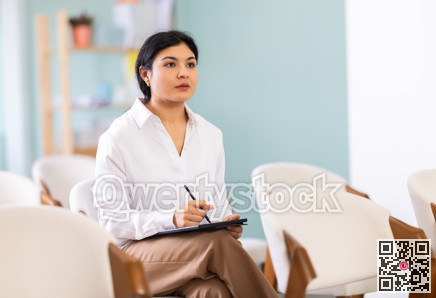 During lecture meeting, female pupil listen to teacher and write down summary in tablet