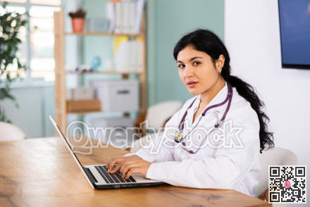 Female doctor works on laptop in room