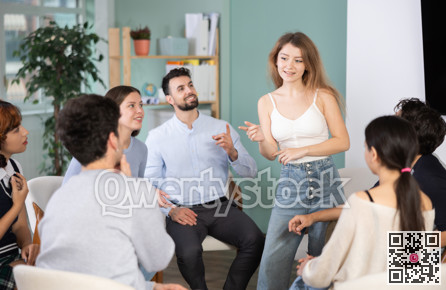 Young girl standing and talking to students sitting in a circle