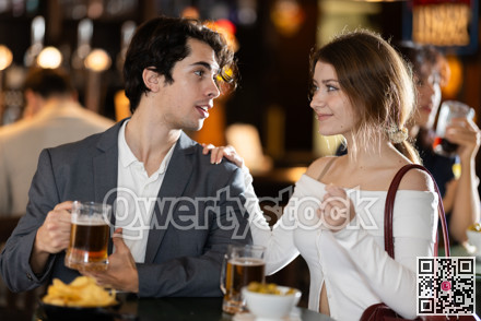Young couple sitting at bar table drinking beer and talking