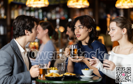 Group of happy friends in bar, drinking beer and having conversation