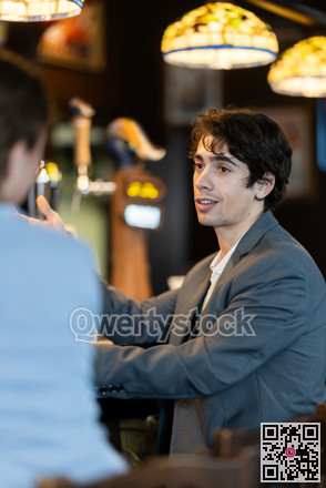 Young man drinking beer and chatting with woman at bar