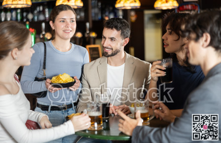 Young friends meeting at table in bar, discussion and drinking beer