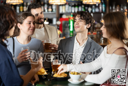 Young friends meeting at table in bar, discussion and drinking beer