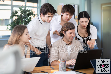 Colleagues looking at one laptop together in office