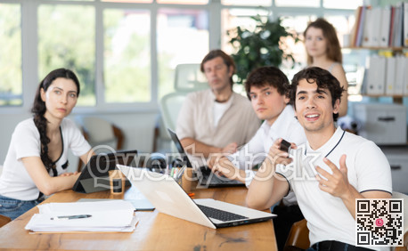 Portrait of group of young businessmen at table watching presentation with interest during business meeting