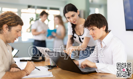 Employees working with laptops and paper documents in office