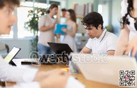 Employees working with laptops and paper documents in office