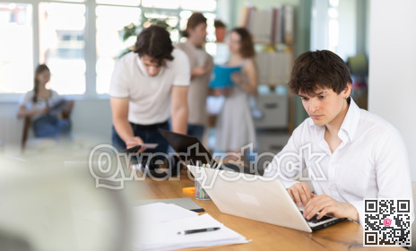 Guy sitting at desk is working on laptop computer.