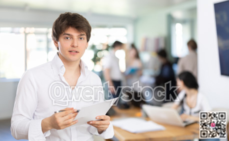 Young man standing in office with paper documents