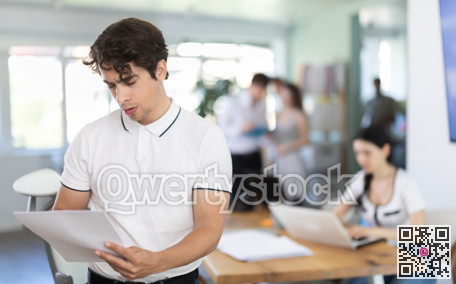 Young man standing in office holds paper documents