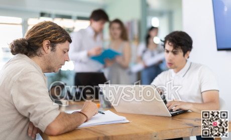 Employees working with laptops and paper documents in office
