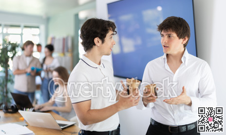 Coffee break - two men drinking coffee and chatting during break in office