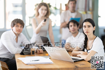 Portrait of group of young businessmen at table watching presentation with interest during business meeting