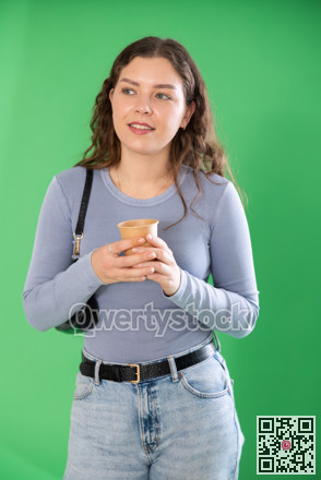 Chroma key compositing. Pretty girl drinking coffee against green chroma key background