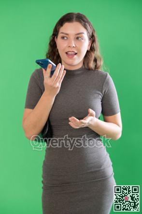 Young woman recording voice message in front of green screen