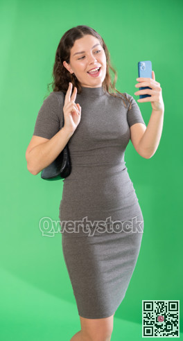 Csmiling pretty girl takes selfie on green background. Chroma key compositing.