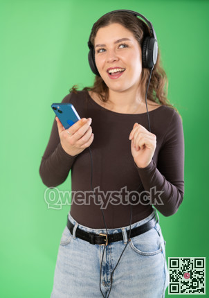 Passionate girl listening to music on headphones on green background. Chroma key compositing.