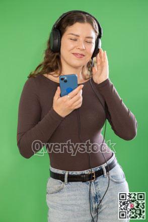 Girl listens to music using wired headphones and mobile phone