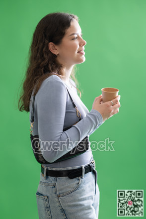 Young woman drinking coffee in front of green screen