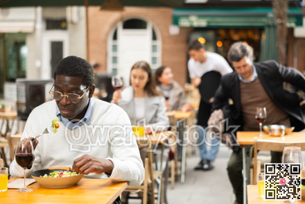 On open area of cafe, African man in restaurant eating salad