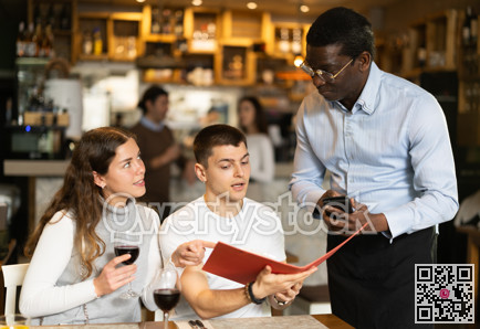 African man listen to restaurant couple customer, writes down order