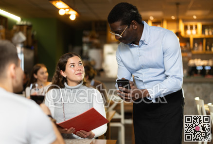 Woman, after reading the menu, makes an order from an African waiter