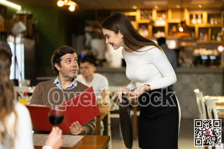 Man, after reading the menu, makes an order from the waitress