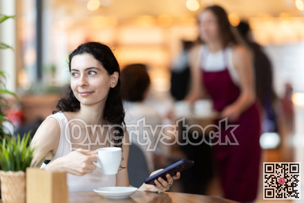 Girl in cafe drinks coffee and calling using mobile phone