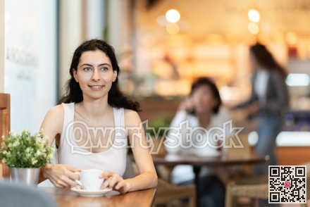 Girl whiles away time and waits for meeting in chain cafe