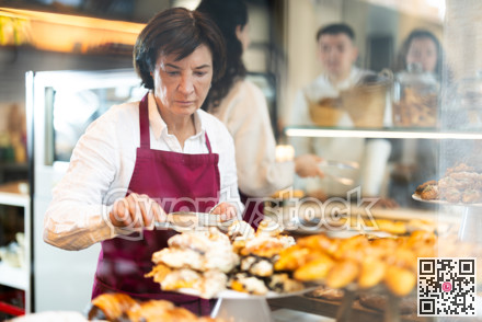 Mature woman seller laying out buns