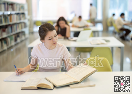 Female student sitting at table and writing