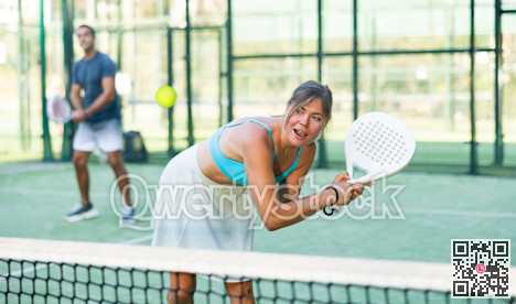 Young woman in skirt playing padel tennis on court
