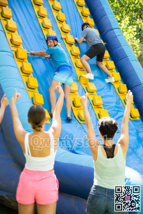 Father and son trying to climb on top of slide in amusement park