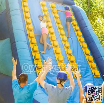 Women using sticks to reach top of slide in adventure park