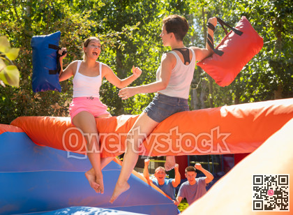 Women holding soft pillows and fighting in adventure park