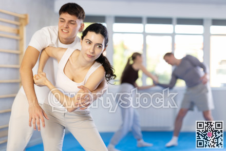 Young girl practicing self-defense techniques in pairs with guy
