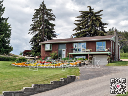 Old residential house in Canada with big flower bed on the front yard