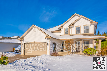 Family house with driveway and front yard in snow on winter sunny day