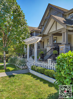 The porch of a nice residential house entrance with wooden gate and white birch in front