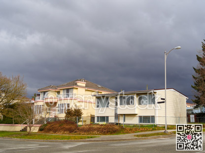The street corner with two residential houses on stormy sky background