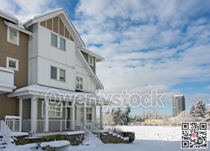 Residential townhouses and high-rise building on bright winter day with cloudy sky background