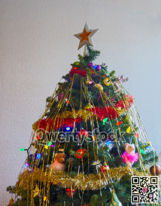 White-golden star and colourful balls with color electtric lights decorating top of Christmas tree