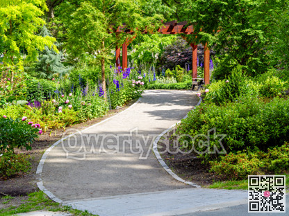 Gravel pathway to the entrance of small city park on sunny summer day